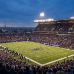 Packed American football stadium at dusk under floodlights with a distant Paris skyline